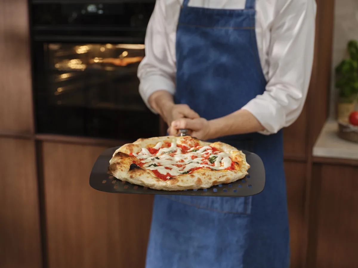 Pizza appena sfornata sulla pala forata davanti al forno Electrolux PizzaExpert Serie 700