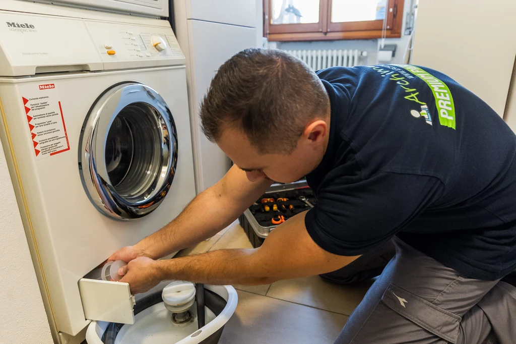 Manutenzione lavatrice Miele a Modena: tecnico FCM durante la pulizia del filtro