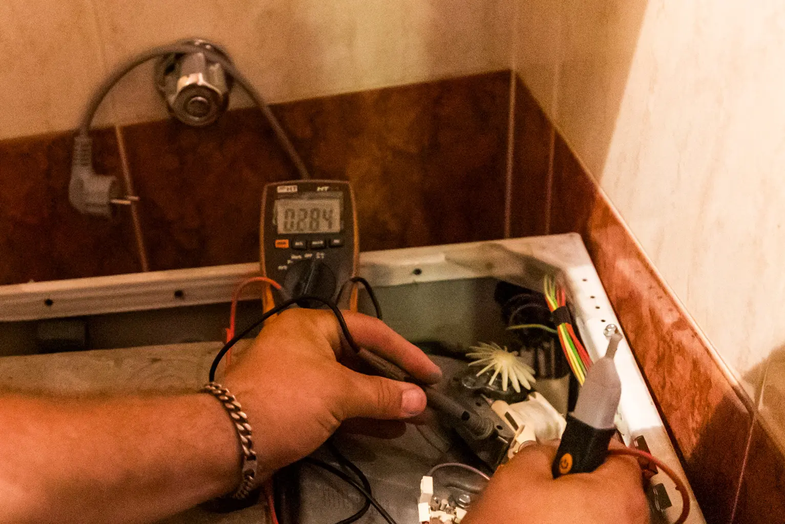 Tecnico della rete Archimede misura con il tester un componente di una lavatrice